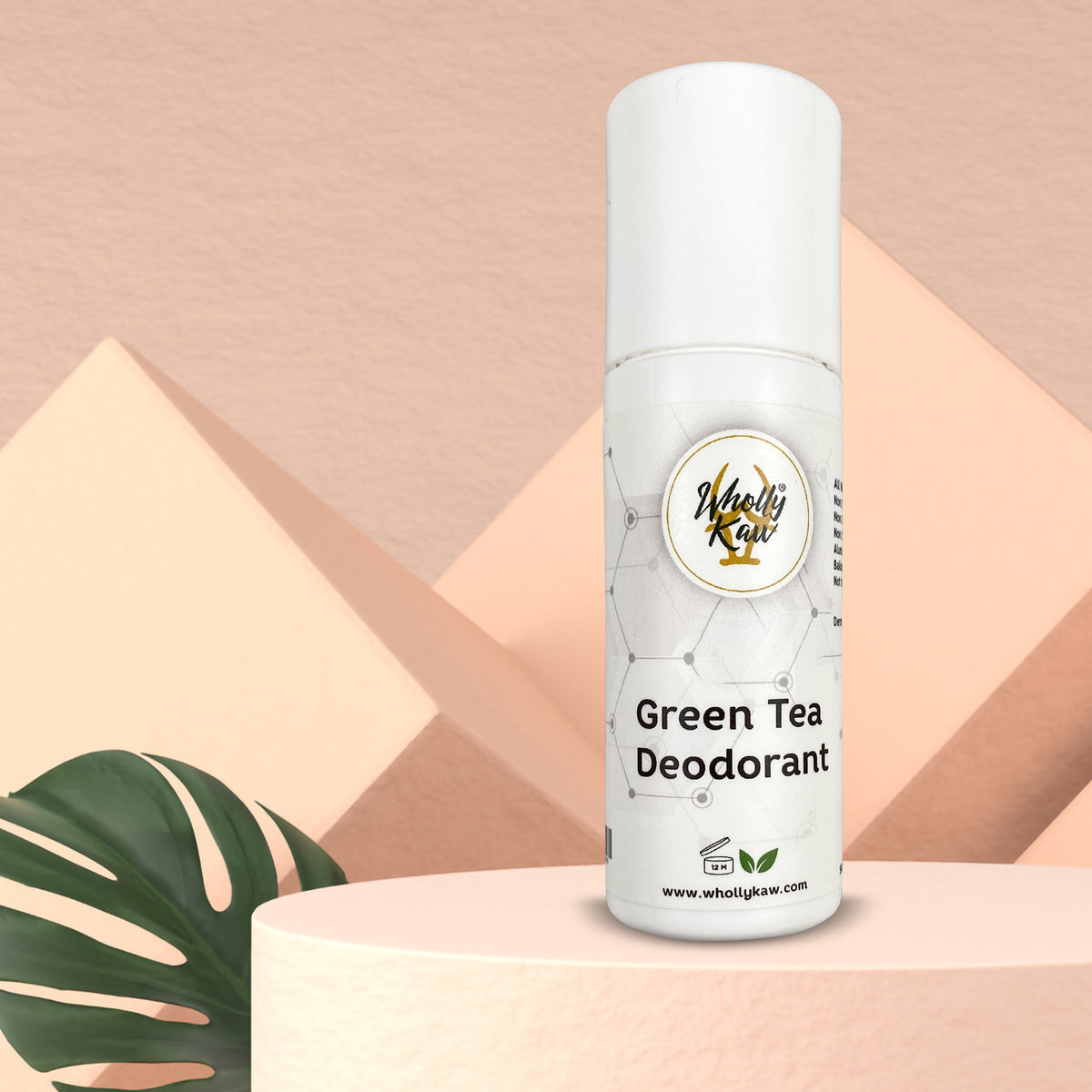 Wholly Kaw Green Tea Deodorant roll-on on a pink pedestal with tropical leaf aluminum-free natural deodorant